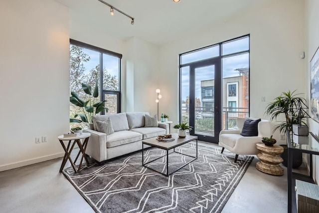 living room featuring track lighting, concrete flooring, and a healthy amount of sunlight