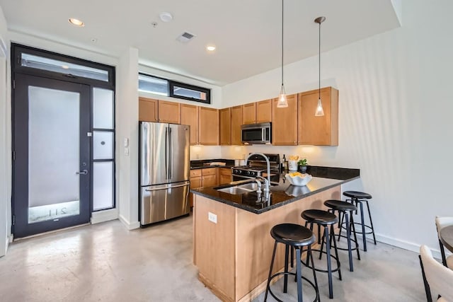 kitchen with stainless steel appliances, sink, kitchen peninsula, a breakfast bar area, and hanging light fixtures