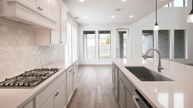 kitchen with a sink, custom exhaust hood, visible vents, light countertops, and appliances with stainless steel finishes
