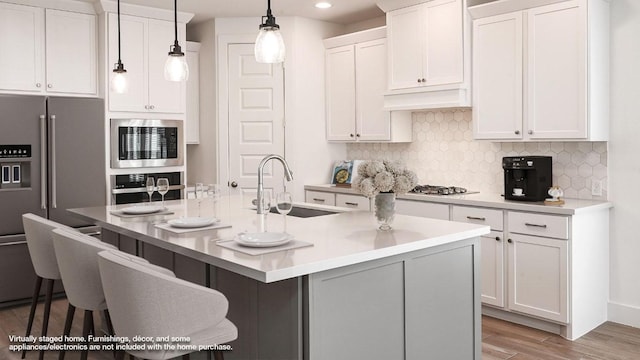 267 Carpenter Hill Dr, Buda, TX 78610 - kitchen with stainless steel appliances, light wood-type flooring, a kitchen breakfast bar, white cabinets, and recessed lighting