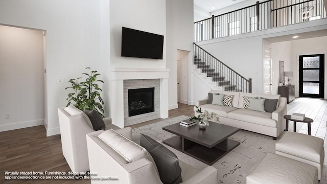 living room with wood finished floors, a high ceiling, and a fireplace