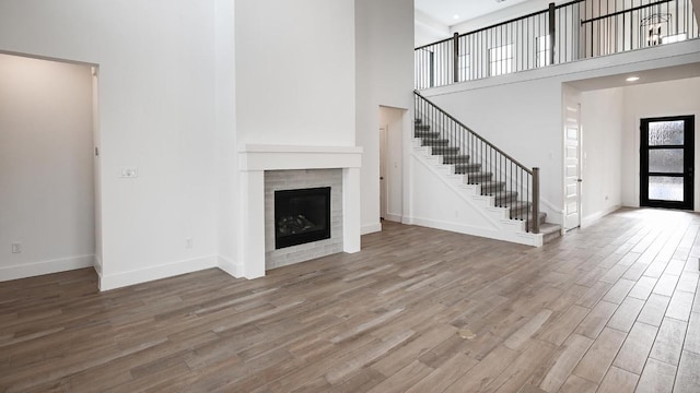 267 Carpenter Hill Dr, Buda, TX 78610 - unfurnished living room featuring stairs, wood finished floors, a towering ceiling, and a fireplace