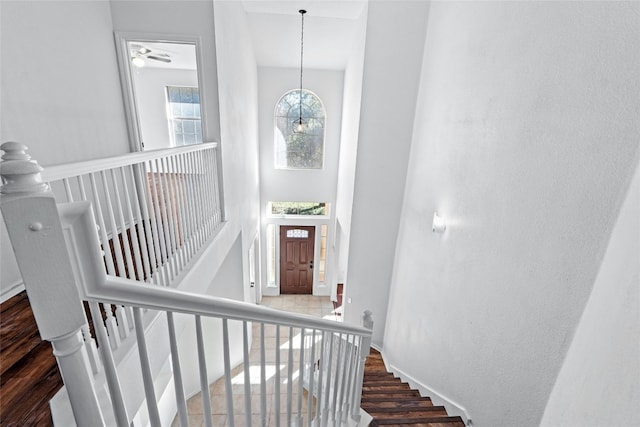 stairway with an inviting chandelier, hardwood / wood-style flooring, and a high ceiling