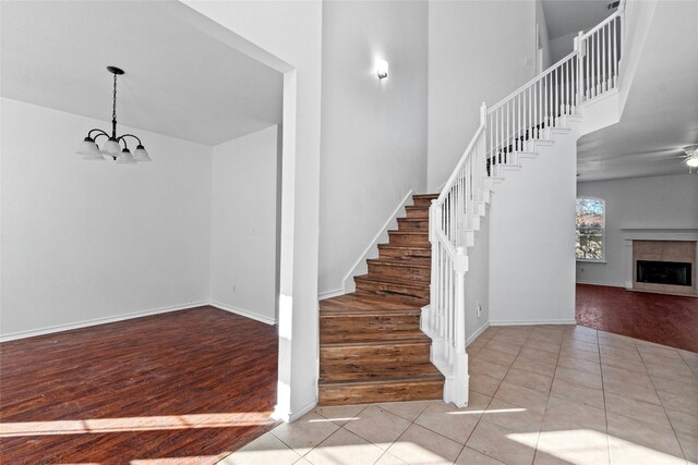 tiled entrance foyer featuring ceiling fan with notable chandelier and a fireplace