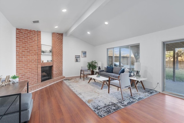 living room with a wealth of natural light, a fireplace, lofted ceiling with beams, and hardwood / wood-style flooring