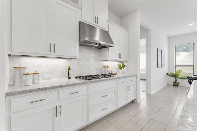 kitchen with decorative backsplash, light stone countertops, white cabinets, and stainless steel gas cooktop