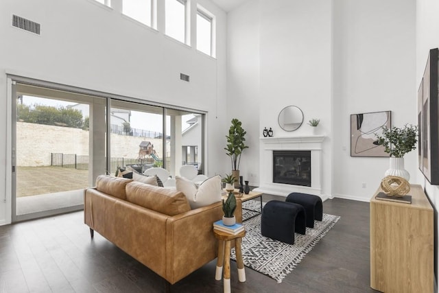 living room with plenty of natural light, dark hardwood / wood-style flooring, and a high ceiling