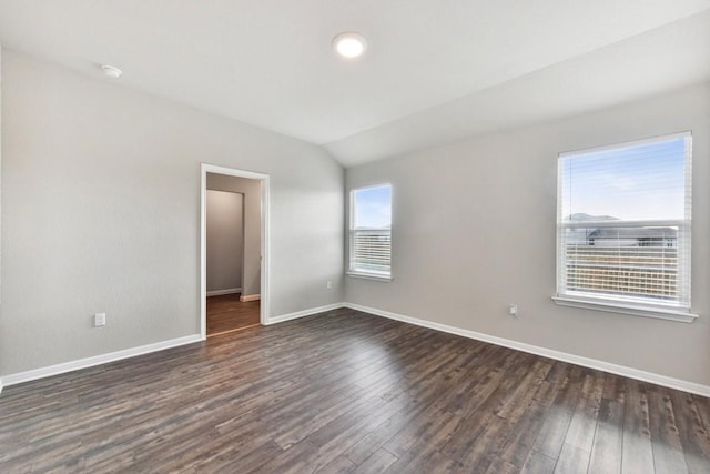 spare room featuring vaulted ceiling and dark wood-type flooring