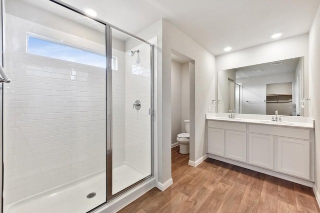 bathroom featuring hardwood / wood-style flooring, vanity, toilet, and a shower with shower door