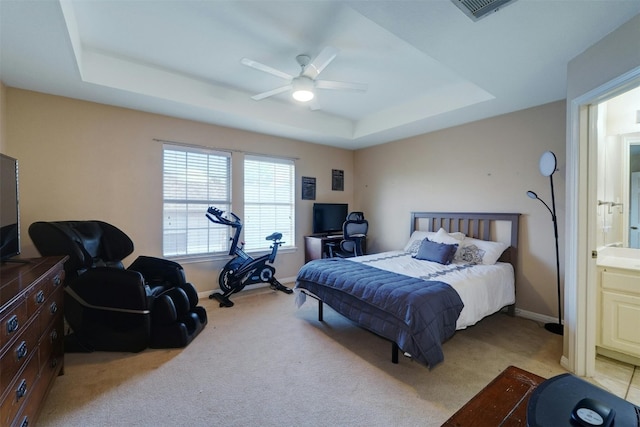 carpeted bedroom featuring ceiling fan, a raised ceiling, and ensuite bath