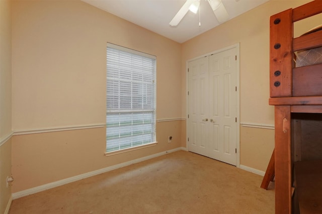 unfurnished bedroom with light carpet, a closet, and ceiling fan