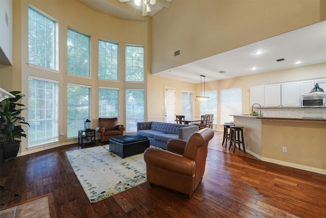 living room featuring ceiling fan, a wealth of natural light, dark wood-type flooring, and a high ceiling