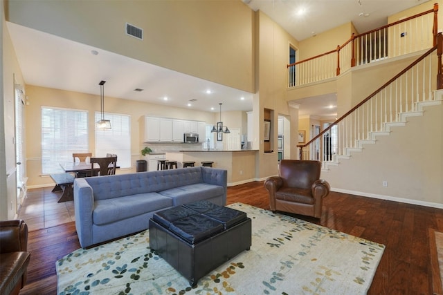 living room with dark hardwood / wood-style flooring and a towering ceiling