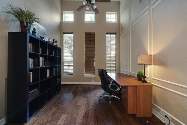 office area with ceiling fan, dark hardwood / wood-style flooring, and a towering ceiling