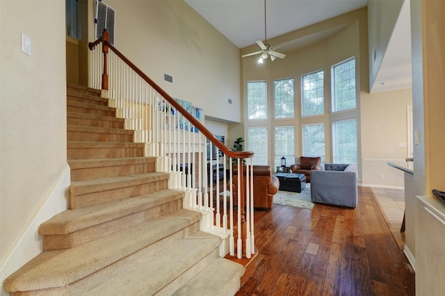 stairs featuring ceiling fan, a towering ceiling, and hardwood / wood-style flooring