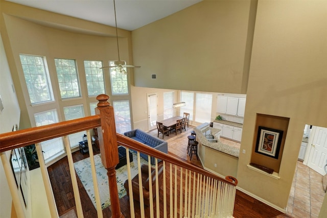 stairway with hardwood / wood-style flooring, ceiling fan, sink, and a high ceiling