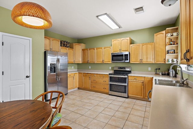 kitchen with appliances with stainless steel finishes, light brown cabinets, light tile patterned floors, and sink