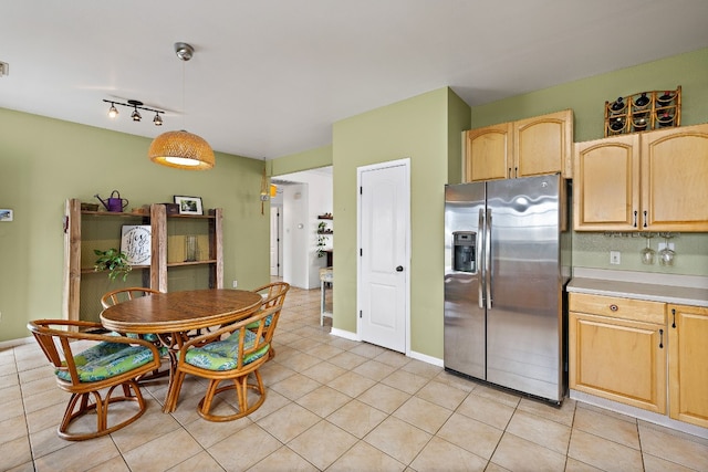 kitchen with stainless steel fridge, light brown cabinets, decorative light fixtures, and light tile patterned floors