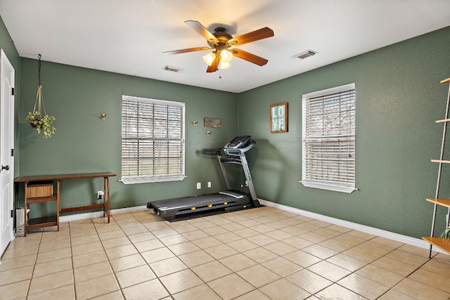 exercise area featuring light tile patterned floors and ceiling fan