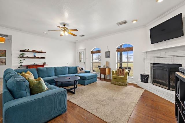 living room with ceiling fan, a fireplace, crown molding, and dark hardwood / wood-style floors