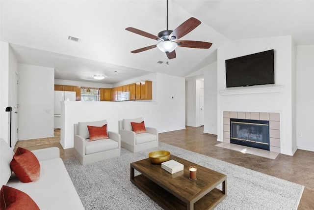 living room featuring ceiling fan, a tile fireplace, and vaulted ceiling