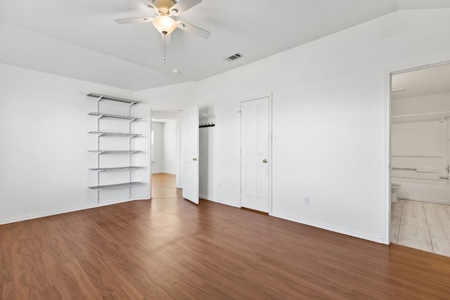 unfurnished bedroom with ensuite bathroom, dark hardwood / wood-style flooring, and ceiling fan