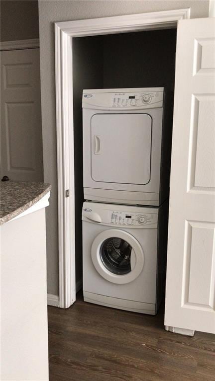 washroom with dark hardwood / wood-style floors and stacked washer and dryer