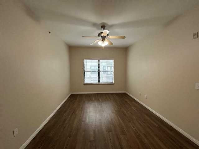 empty room featuring baseboards, dark wood finished floors, and a ceiling fan