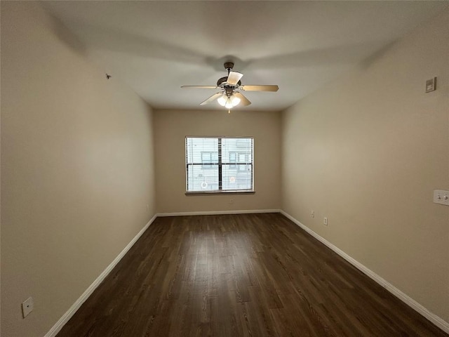 empty room with dark wood finished floors, a ceiling fan, and baseboards