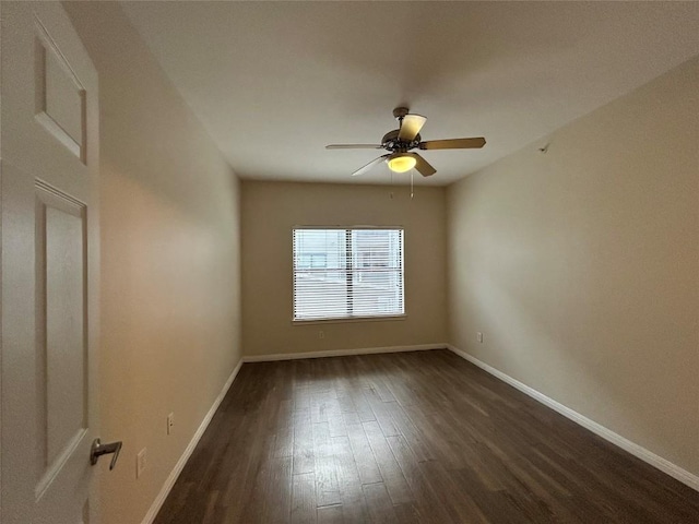 spare room featuring dark wood-style floors, a ceiling fan, and baseboards