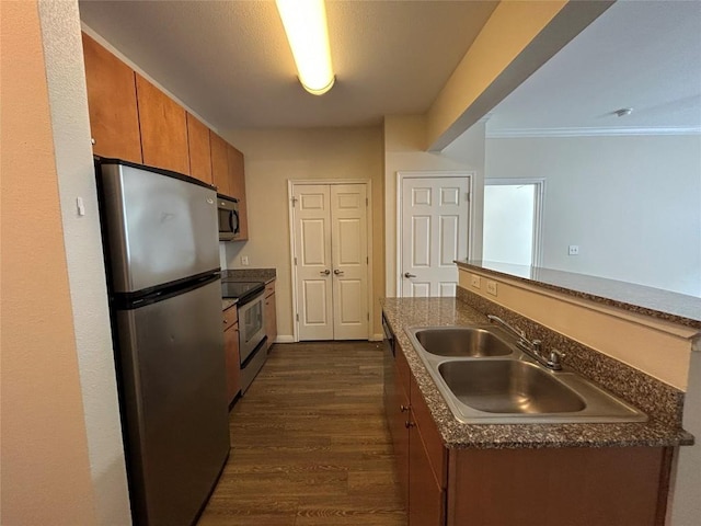 kitchen featuring a sink, dark countertops, dark wood finished floors, stainless steel appliances, and brown cabinetry