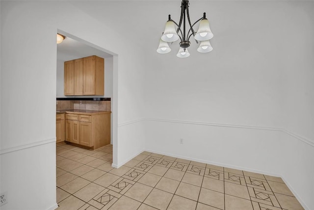 unfurnished dining area featuring light tile patterned floors and a chandelier