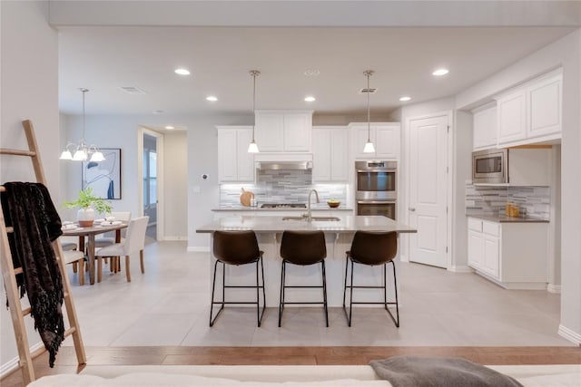 kitchen with stainless steel appliances, sink, pendant lighting, a center island with sink, and white cabinets