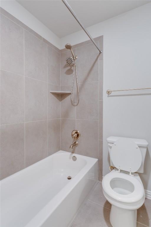 bathroom with tile patterned flooring, toilet, and tiled shower / bath