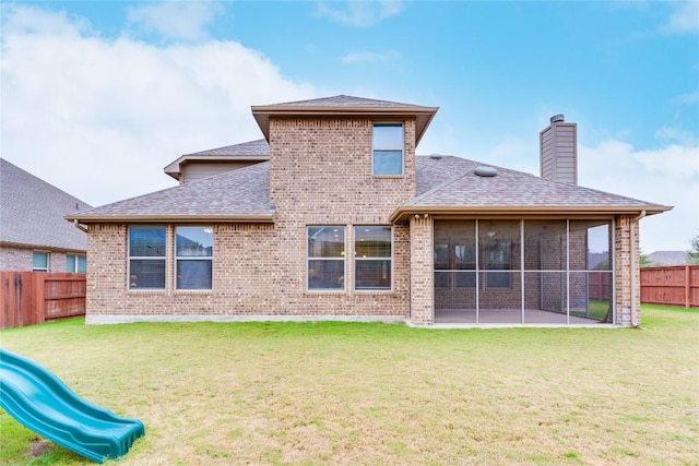 back of house featuring a lawn and a playground