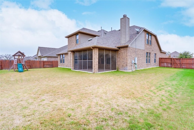 back of house with a sunroom, a playground, and a lawn