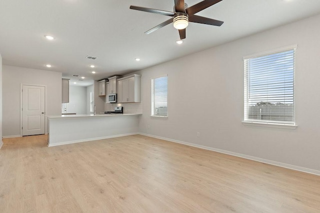 unfurnished living room featuring ceiling fan and light hardwood / wood-style flooring