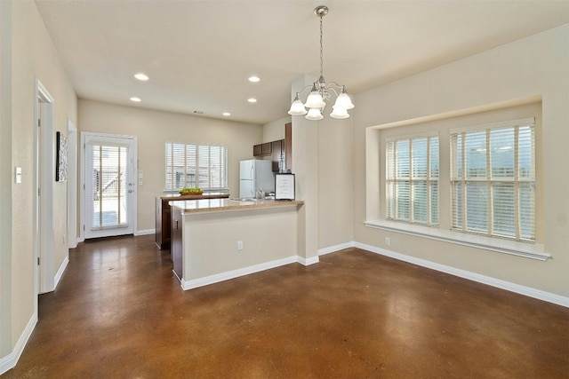 kitchen with kitchen peninsula, decorative light fixtures, white fridge, and a notable chandelier