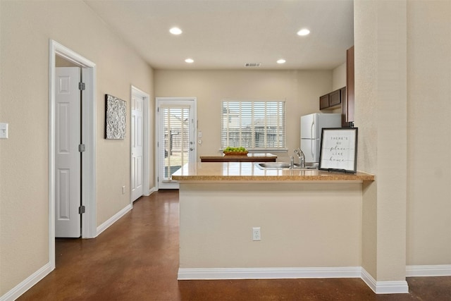 kitchen with kitchen peninsula, sink, and white fridge