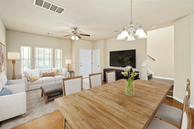 dining space with ceiling fan with notable chandelier