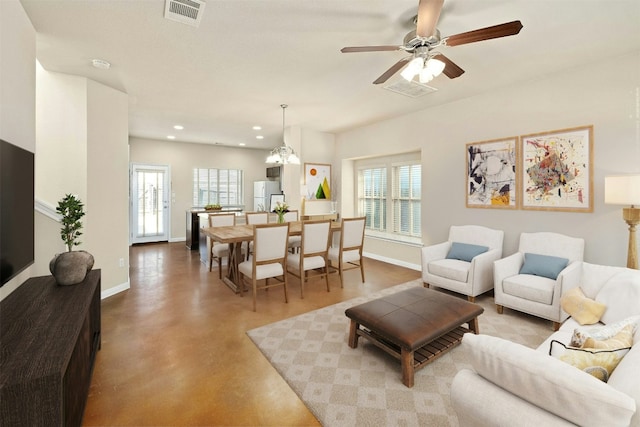 living room featuring ceiling fan with notable chandelier and concrete flooring