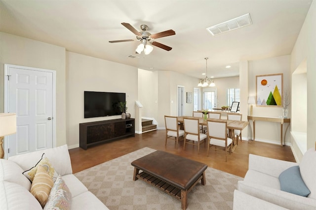 living room featuring ceiling fan with notable chandelier and hardwood / wood-style flooring