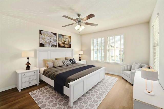 bedroom with hardwood / wood-style floors, ceiling fan, and a textured ceiling