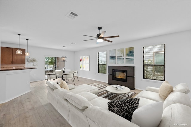 living room featuring ceiling fan, a healthy amount of sunlight, and light wood-type flooring