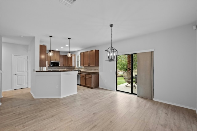 kitchen featuring an inviting chandelier, hanging light fixtures, light hardwood / wood-style flooring, decorative backsplash, and appliances with stainless steel finishes