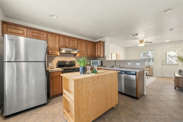 kitchen with butcher block counters, ceiling fan, a center island, and appliances with stainless steel finishes