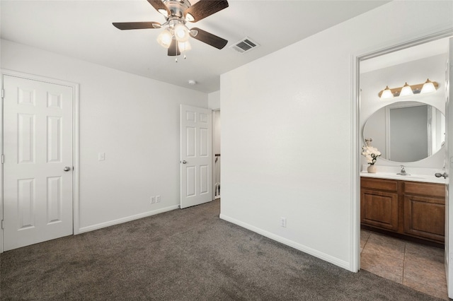 unfurnished bedroom with connected bathroom, ceiling fan, sink, and dark carpet