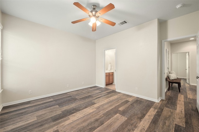 unfurnished bedroom featuring ceiling fan, ensuite bathroom, and dark wood-type flooring