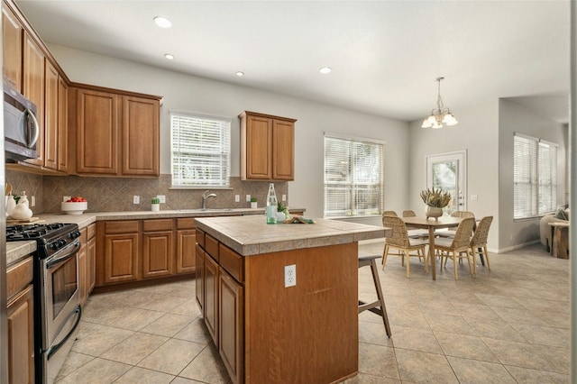 kitchen featuring an inviting chandelier, hanging light fixtures, light tile patterned floors, a kitchen island, and stainless steel appliances