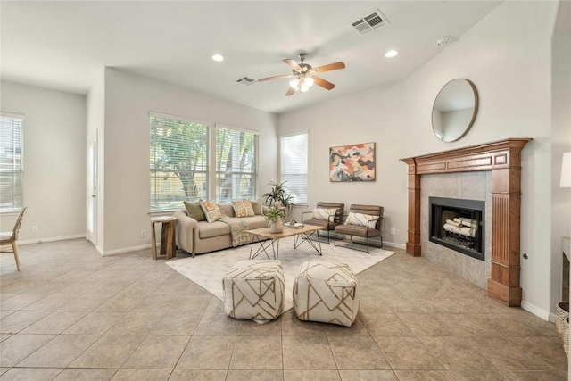 living room with a tiled fireplace, ceiling fan, and light tile patterned floors